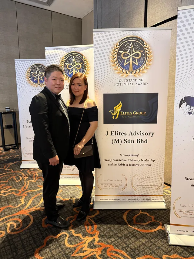 Jay Teh and a guest beside the J Elites Advisory award banner at the ceremony